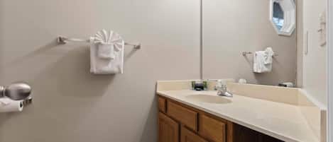 A bathroom with a large mirror, a sink, wooden cabinets, and two towel racks.