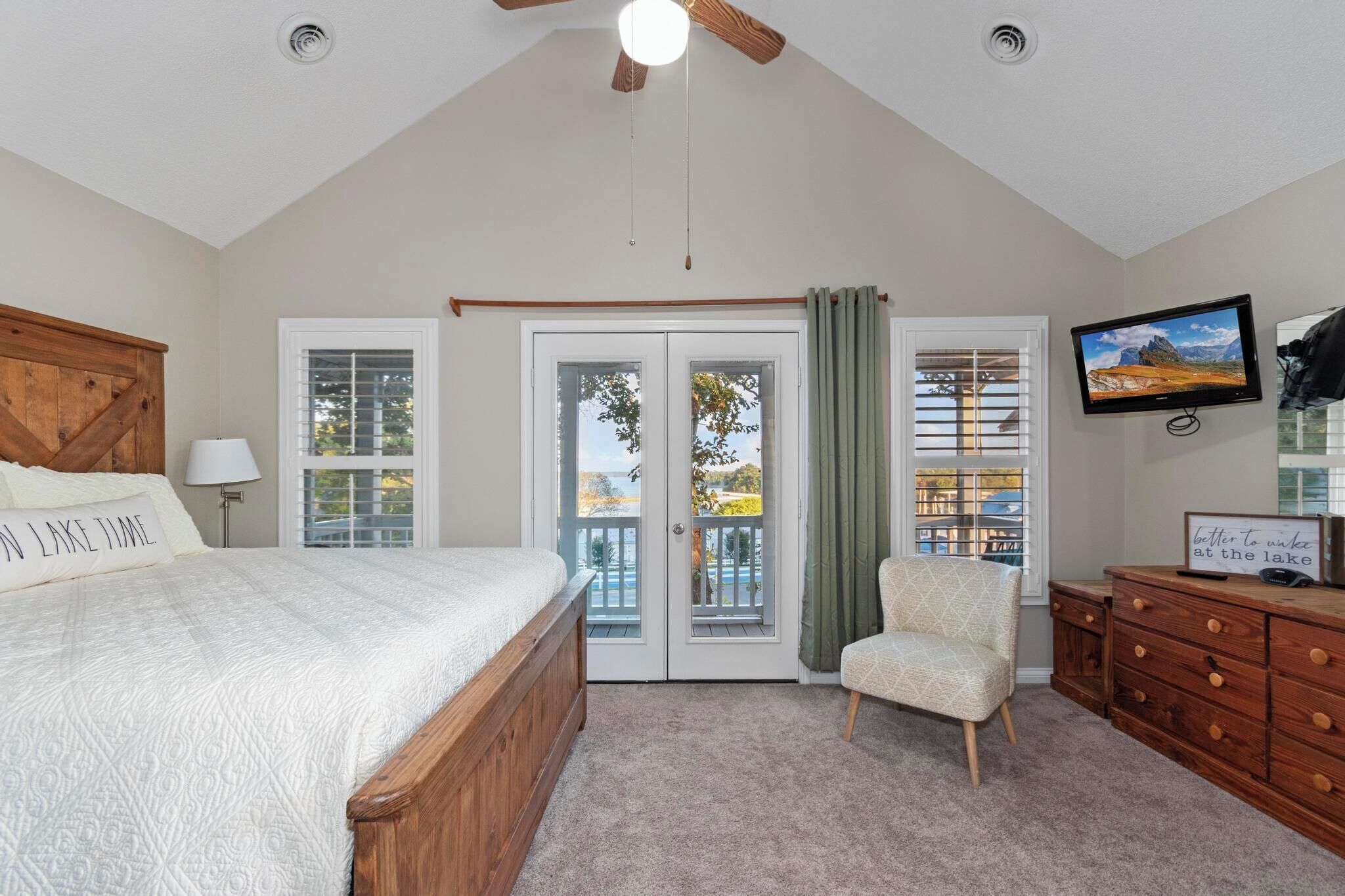 A bedroom with a large bed, a ceiling fan, a TV, a dresser, and a chair.