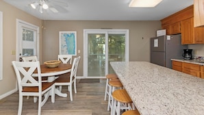 A modern kitchen with a large island, white cabinetry, and a ceiling fan. - Two Bedroom Harbor View Condo (Grand Rivers)