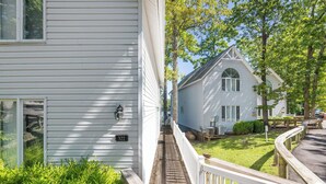 Une maison blanche avec le numéro 322 sur la porte, une terrasse en bois et une cour gazonnée.