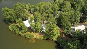 An aerial view of a lakeside property with several houses surrounded by dense greenery and trees.
