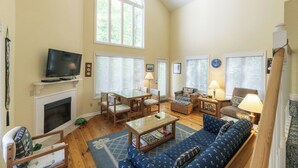 A spacious living room with a fireplace, a television, a dining area, and a large window. - Two Bedroom Bayside Condo (Grand Rivers)