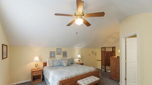 A bedroom with a bed, bedside lamps, a ceiling fan, a bench, and a wardrobe. - Two Bedroom Bayside Condo (Grand Rivers)