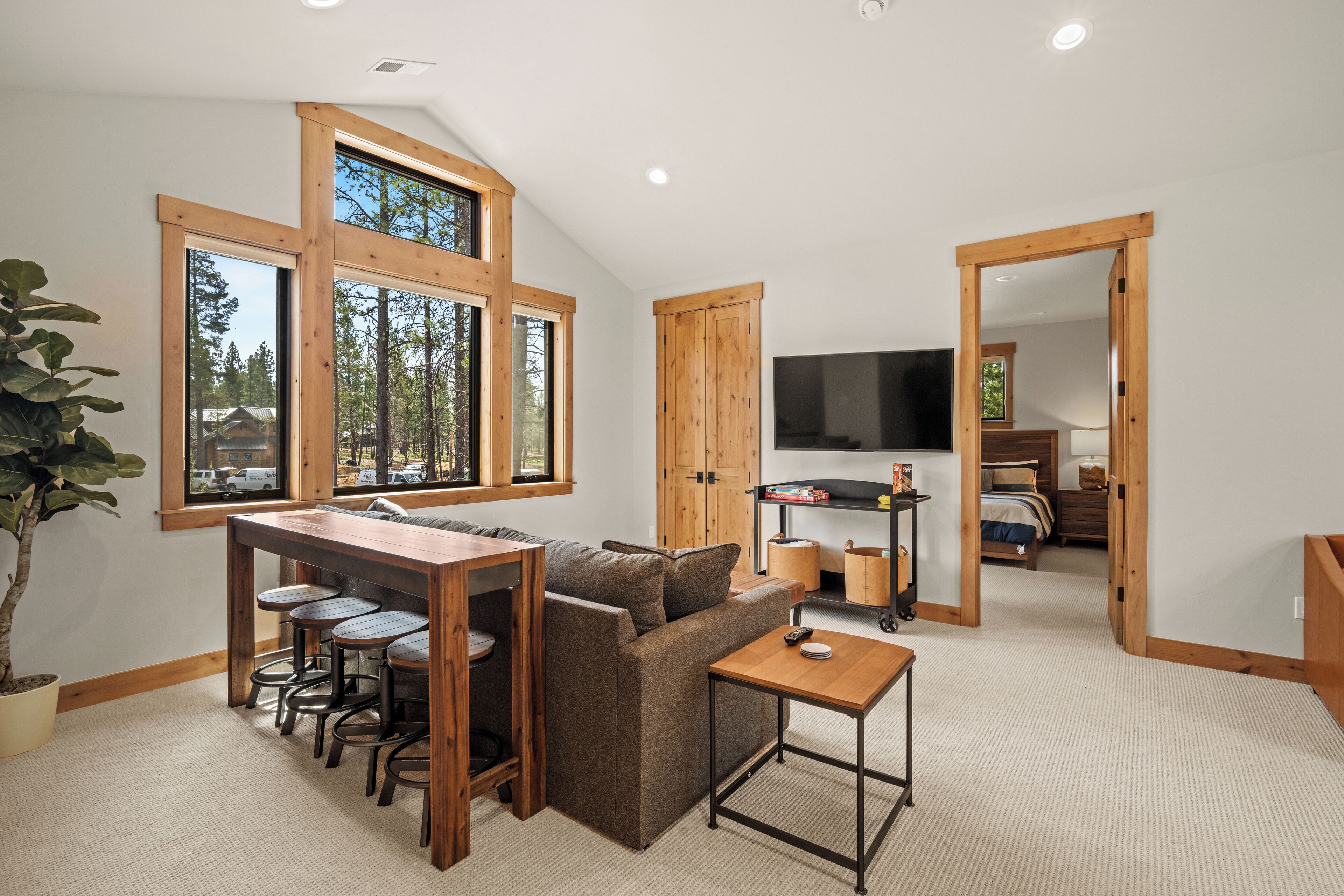 A spacious living area with a wooden dining table, a sofa, and a TV in the background.
