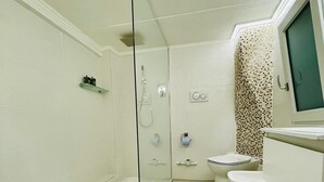 Ein modernes Badezimmer mit einer Duschkabine, einer Toilette und einem Waschbecken mit Spiegel.