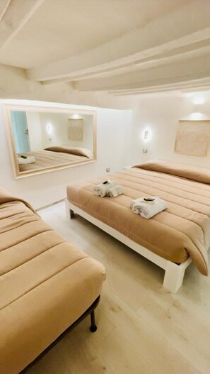 A modern bedroom with a large bed, a smaller sofa, a mirror, and a wall-mounted light fixture. - Casa Cartoleria 34 (Bologna)