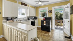 A kitchen with white cabinets, a central island, a black stove, and a ceiling fan.