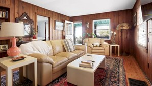 A cozy living room with a beige leather sofa, a white coffee table, and a patterned rug.