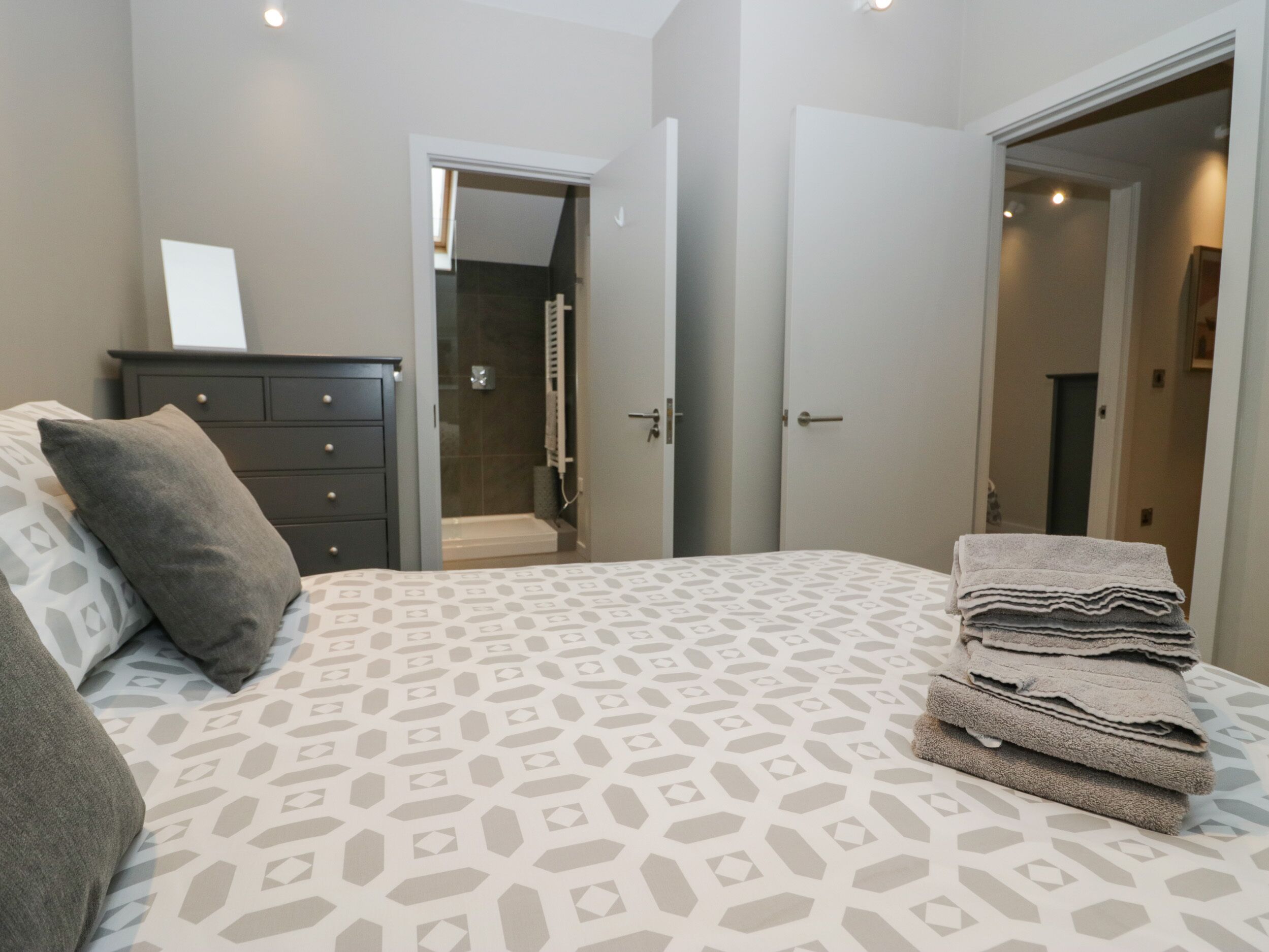 Une chambre à coucher comprenant un lit, une commode, une douche et une porte donnant sur une autre pièce.
