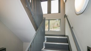 A staircase with metal railings and a view of the outdoors through a window. - Brimstone (Ulverston)