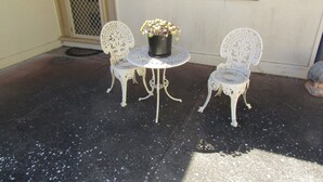 A patio with two white metal chairs and a small round table with a flower pot. - The Shack at Stansbury - Short walk to the beach! Off peak special! (Stansbury)