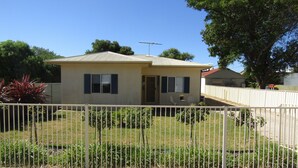 A single-story house with a fenced yard, a small porch, and a satellite dish. - The Shack at Stansbury - Short walk to the beach! Off peak special! (Stansbury)