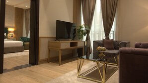 A modern hotel room with a wooden desk, a flat-screen TV, a sofa, and a coffee table. - Watercress Hotels and Signature (Lagos)