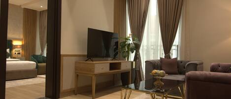 Una camera d'albergo moderna con una scrivania in legno, una TV a schermo piatto, un divano e un tavolino da caffè.