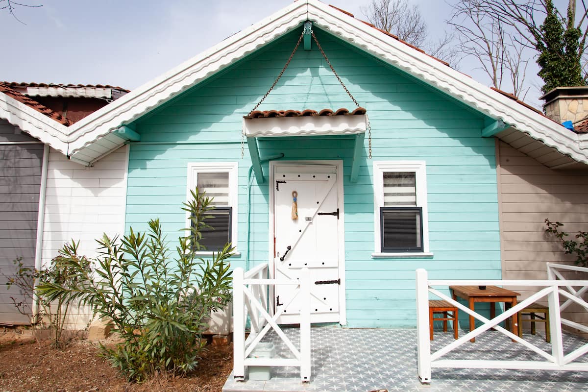 A turquoise house with a white door and a small porch area.