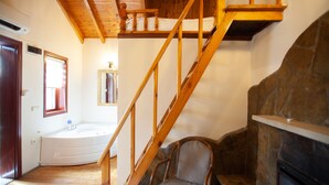 A room with a wooden staircase, a stone fireplace, a bathtub, and a chair. - Ağva Tias Shelale Otel (Sile)