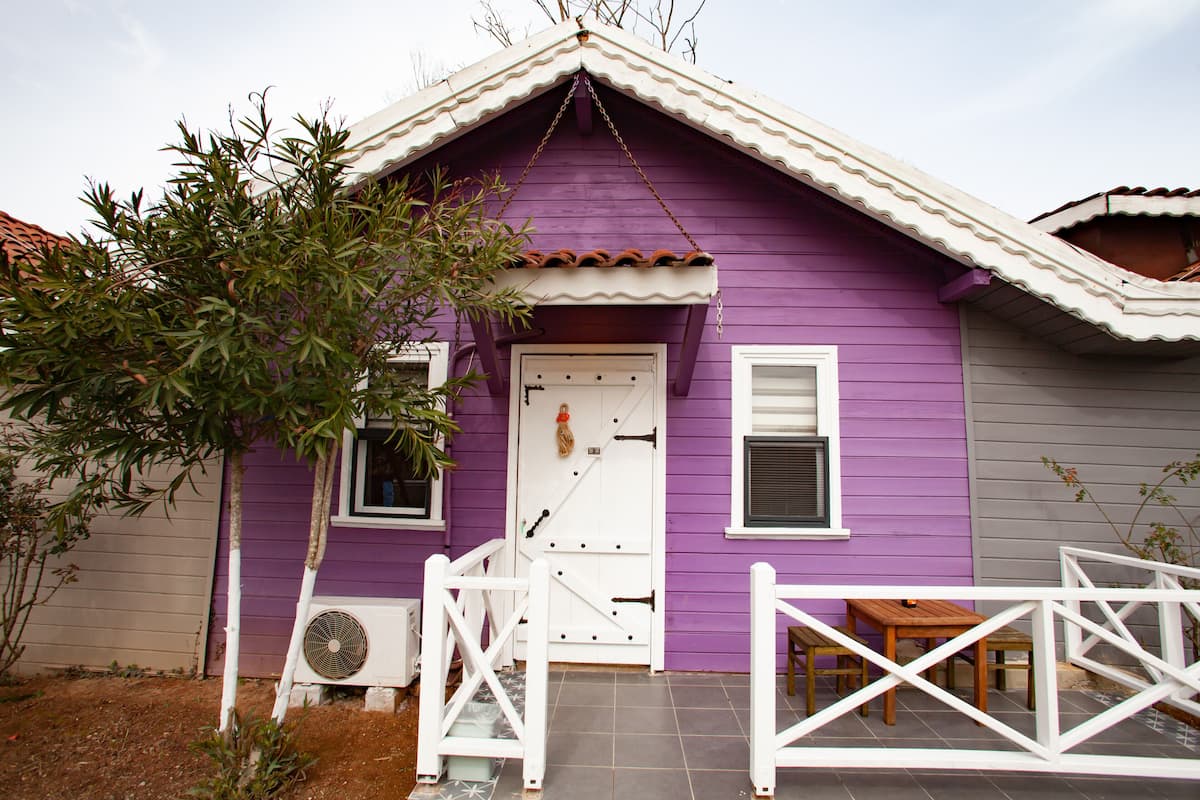 A purple house with a white door, a small porch, and a fan.