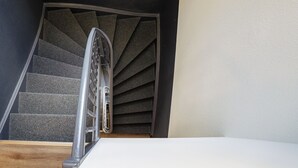 A staircase with a metal handrail and carpeted steps leading to a landing.