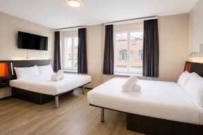 Een hotelkamer met twee bedden, een televisie en een raam met gordijnen.