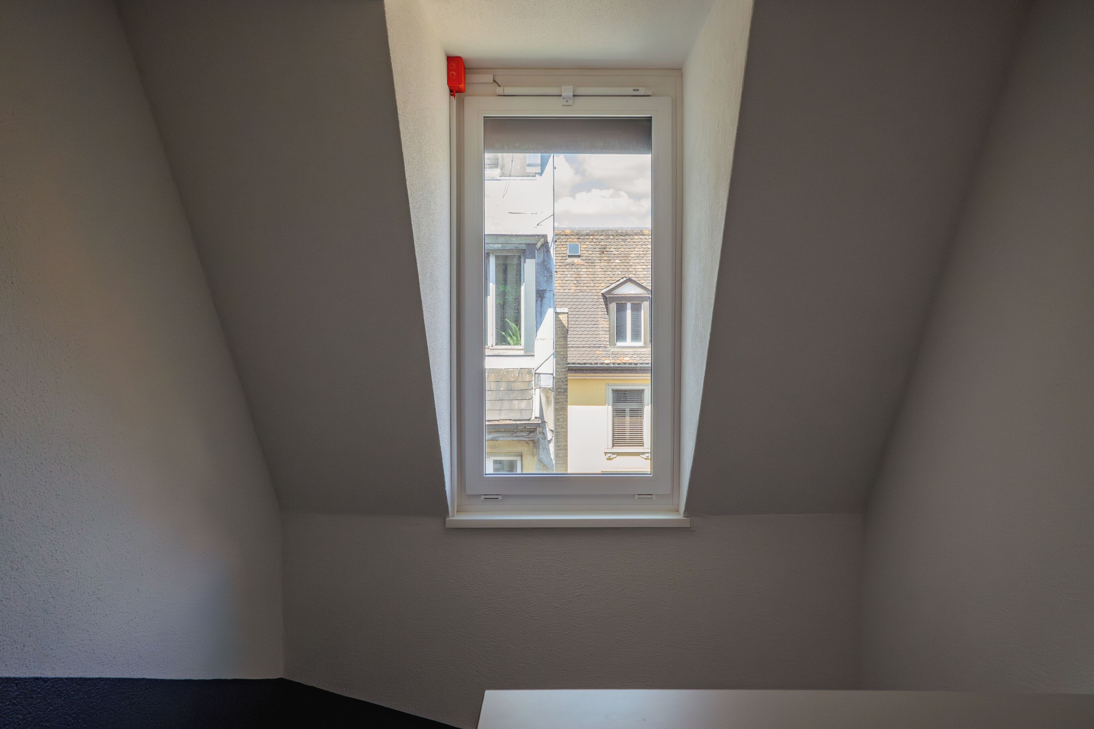 Un tragaluz en una habitación con techos inclinados, que permite el ingreso de luz natural.