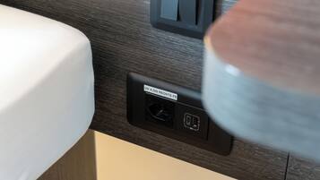 A bathroom with a dark wood-textured wall, a white sink, and a black electrical outlet with a label.