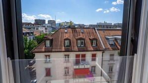 A view from a window of a building with a red-tiled roof, multiple windows, and balconies.