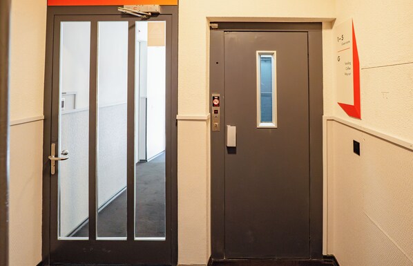 A hallway with two doors, one with a glass panel and the other with a window. - easyHotel Zurich City Main Station (Zürich)