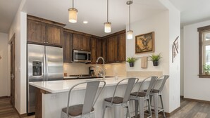 Una cocina moderna con armarios de madera, electrodomésticos de acero inoxidable y una isla central con taburetes de bar.