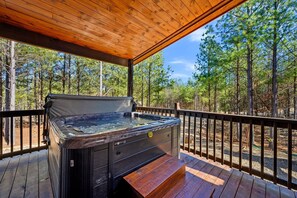 Ein Whirlpool auf einer Holzterrasse mit Blick auf einen Wald.