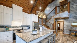 A spacious kitchen with a large island, wooden ceiling, and a staircase leading to an upper level. - 3 bedroom with game room! (Broken Bow)