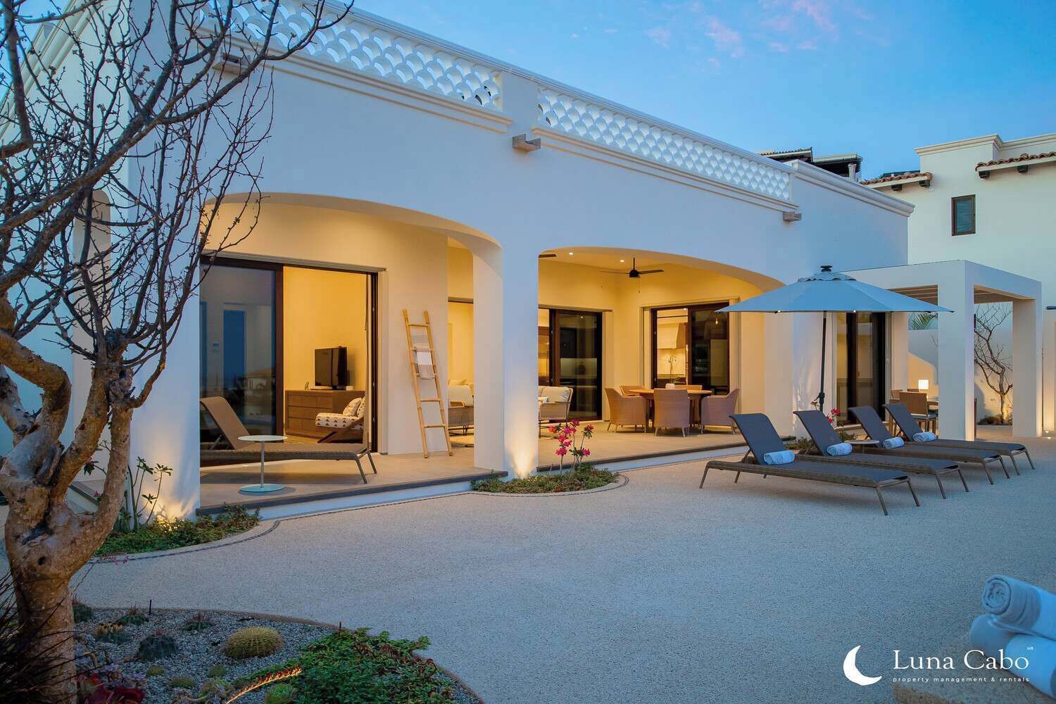En modern villa med en uteplats, utemöbler och en välskött trädgård.