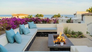 Une terrasse sur le toit avec un foyer, un espace salon et une vue sur la mer.