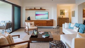 Un salon moderne comprenant un canapé, un fauteuil, une table basse et un coin repas avec une table et des chaises.
