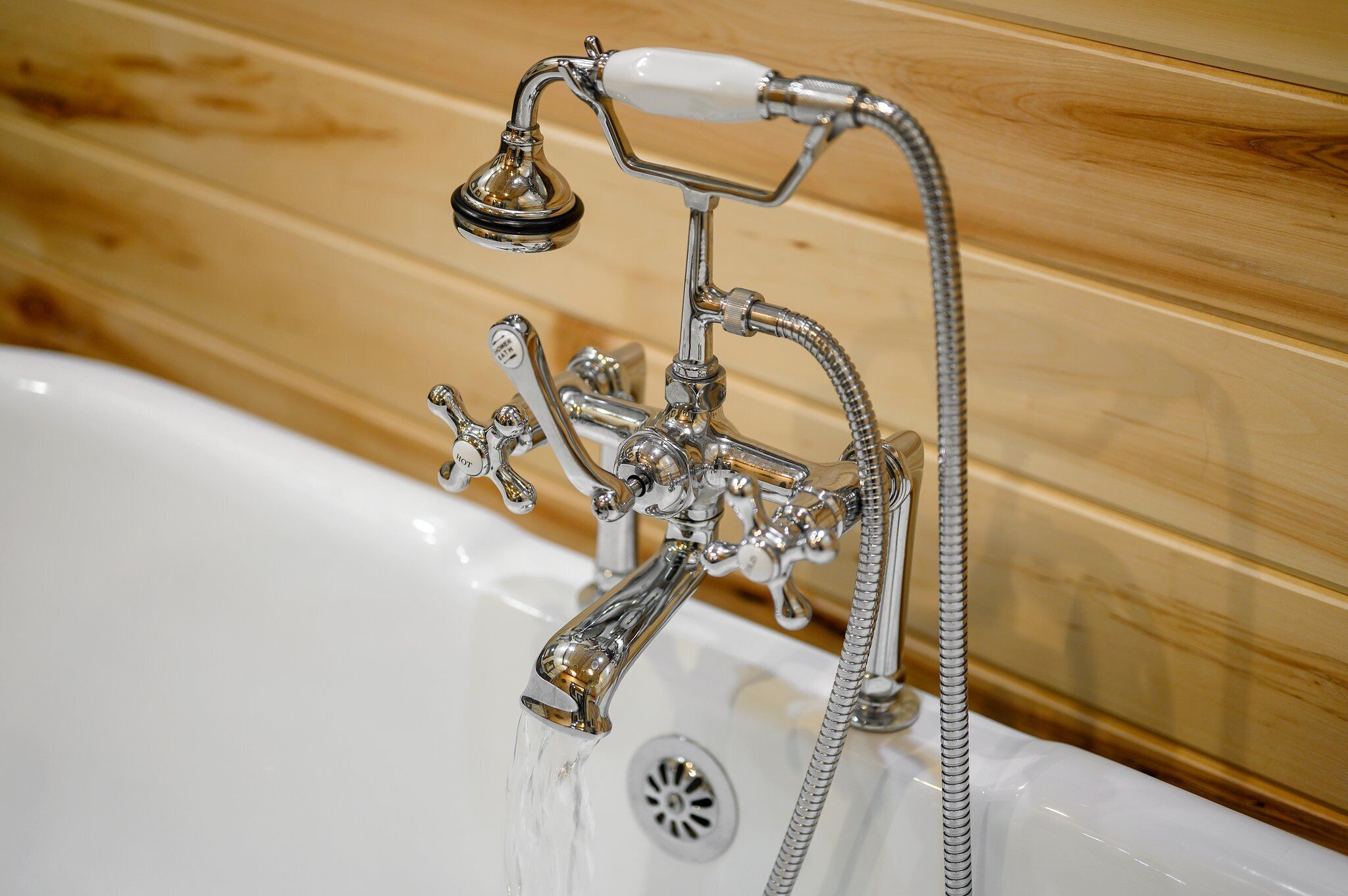 A bathroom with a chrome showerhead, a handheld shower, and a wall-mounted faucet.