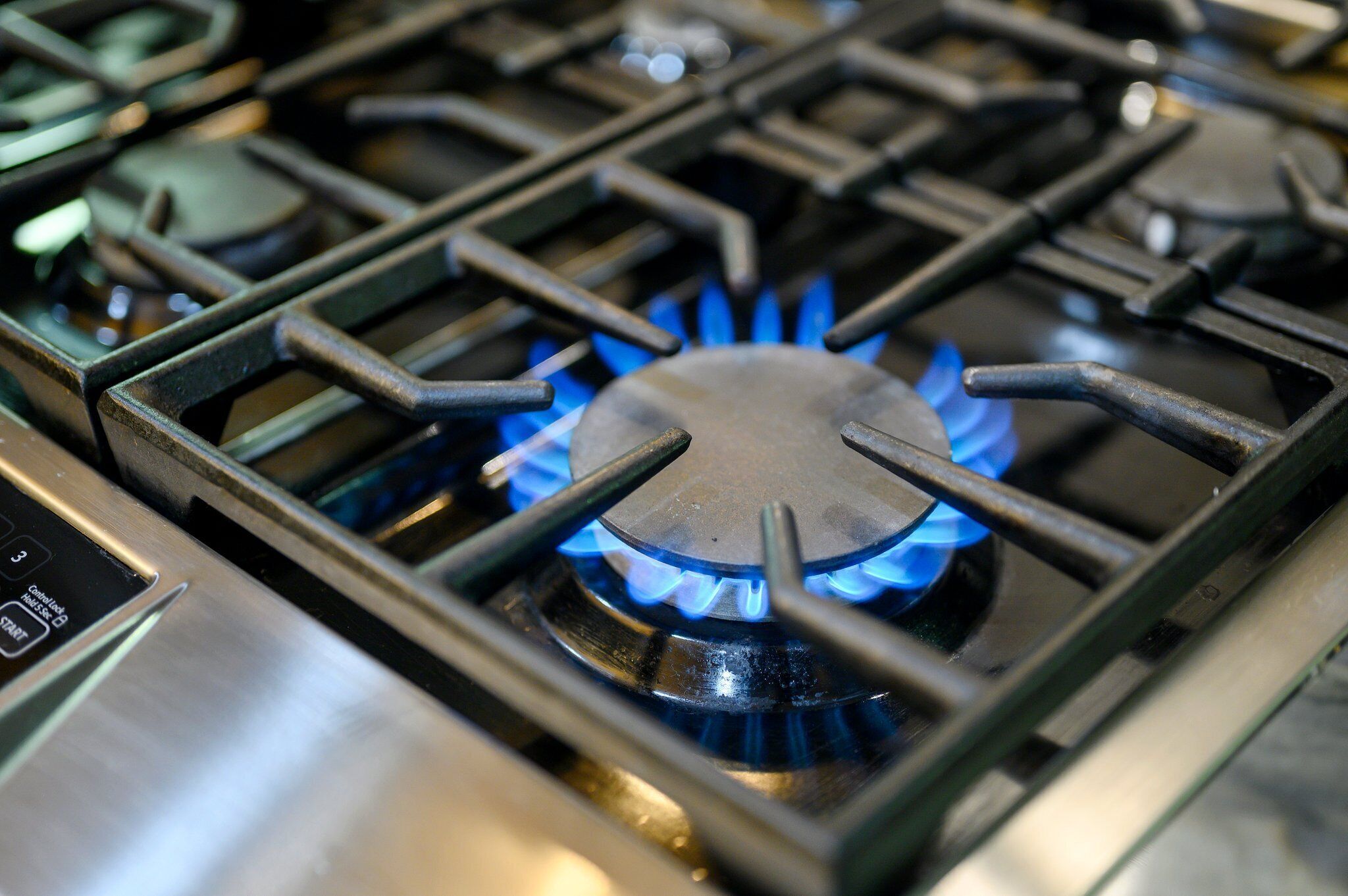 A gas stove with four burners and a visible flame.