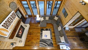 Une cabane dotée d’une cheminée en pierre, d’une grande terrasse en bois et d’un coin salon confortable avec un canapé et un tapis.