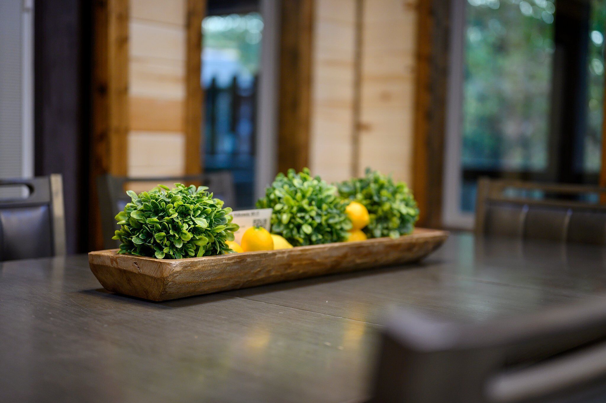 A wooden tray with small potted plants and lemons on a table.