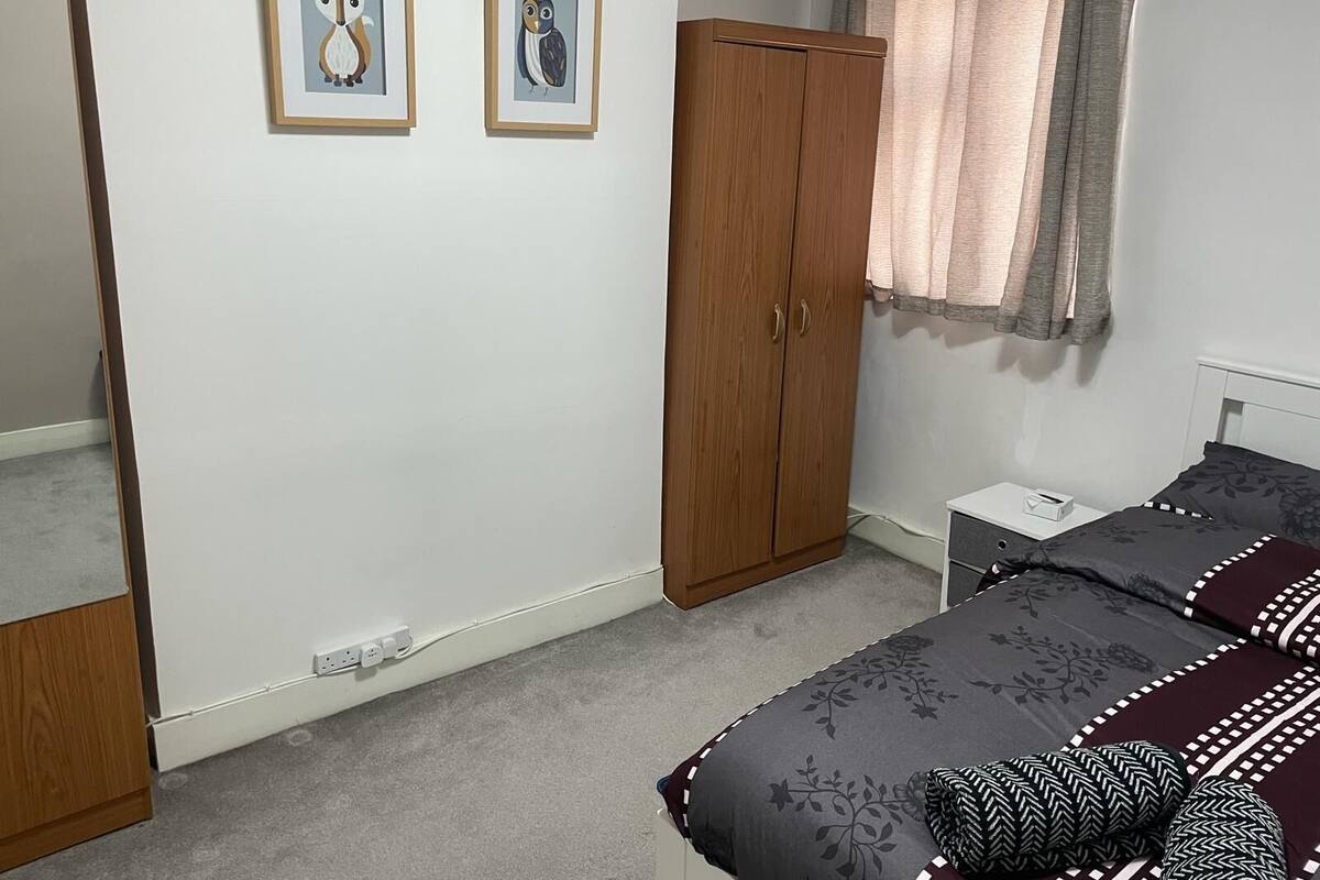 Un dormitorio con cama, armario, mesita de noche y dos cuadros en la pared.