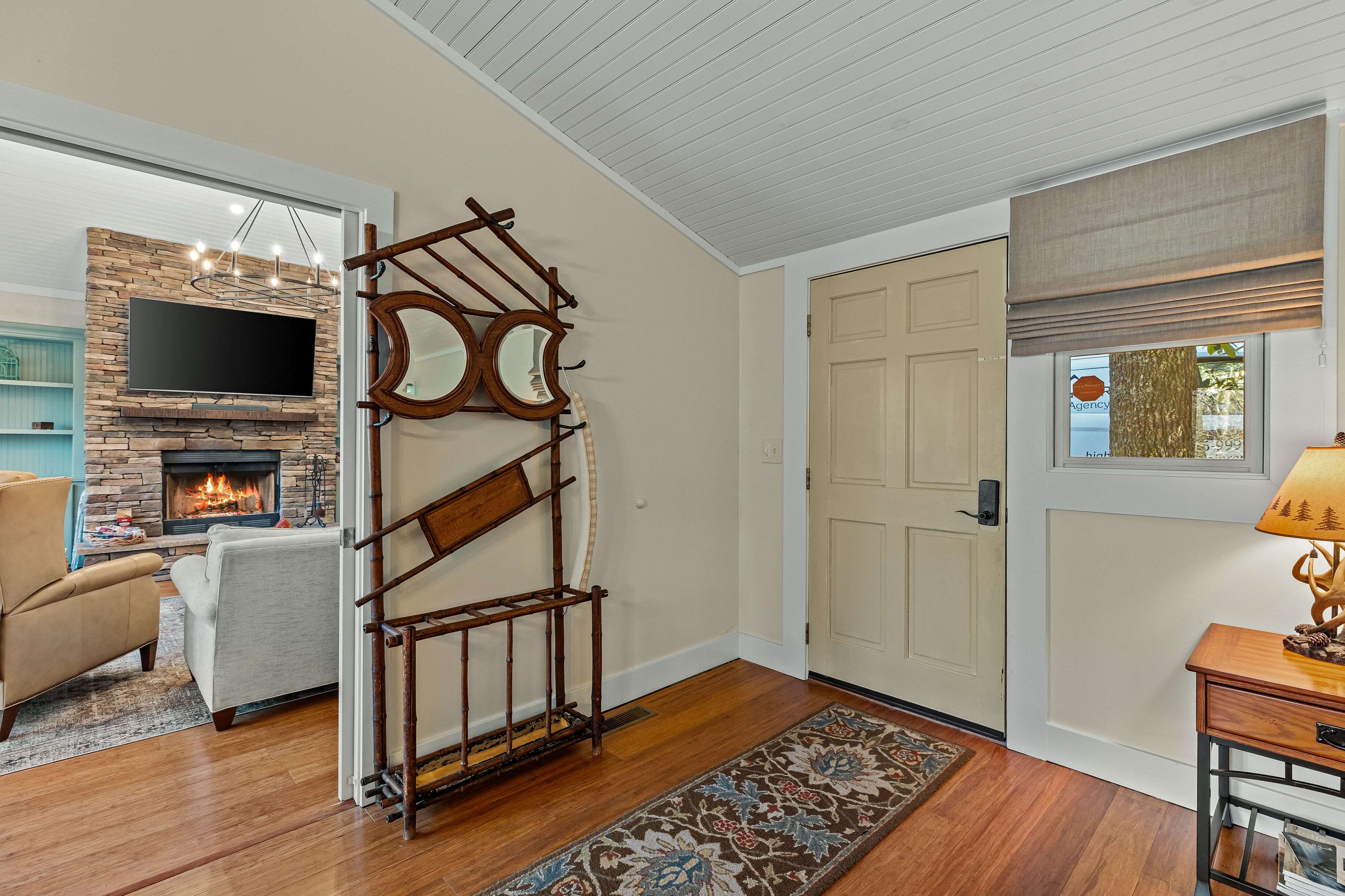 A living room with a stone fireplace, a TV mounted above it, and a wooden ladder leaning against the wall.