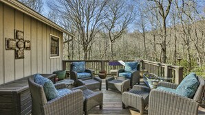 A covered outdoor deck with wicker furniture and a wooden railing. - Duck's Nest 3BR: Modern Creekside Retreat w/ Large Deck, Private Lower Suite (Highlands)