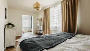 A bedroom with a large bed, a hanging light fixture, a wardrobe, and a window with curtains. - Platz, Charme & ein Hauch Luxus: Happy Place mit Whirlpool, Sauna und Traumblick (Plettenberg)