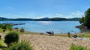 A beach with people, boats, and a clear sky. - Platz, Charme & ein Hauch Luxus: Happy Place mit Whirlpool, Sauna und Traumblick (Plettenberg)