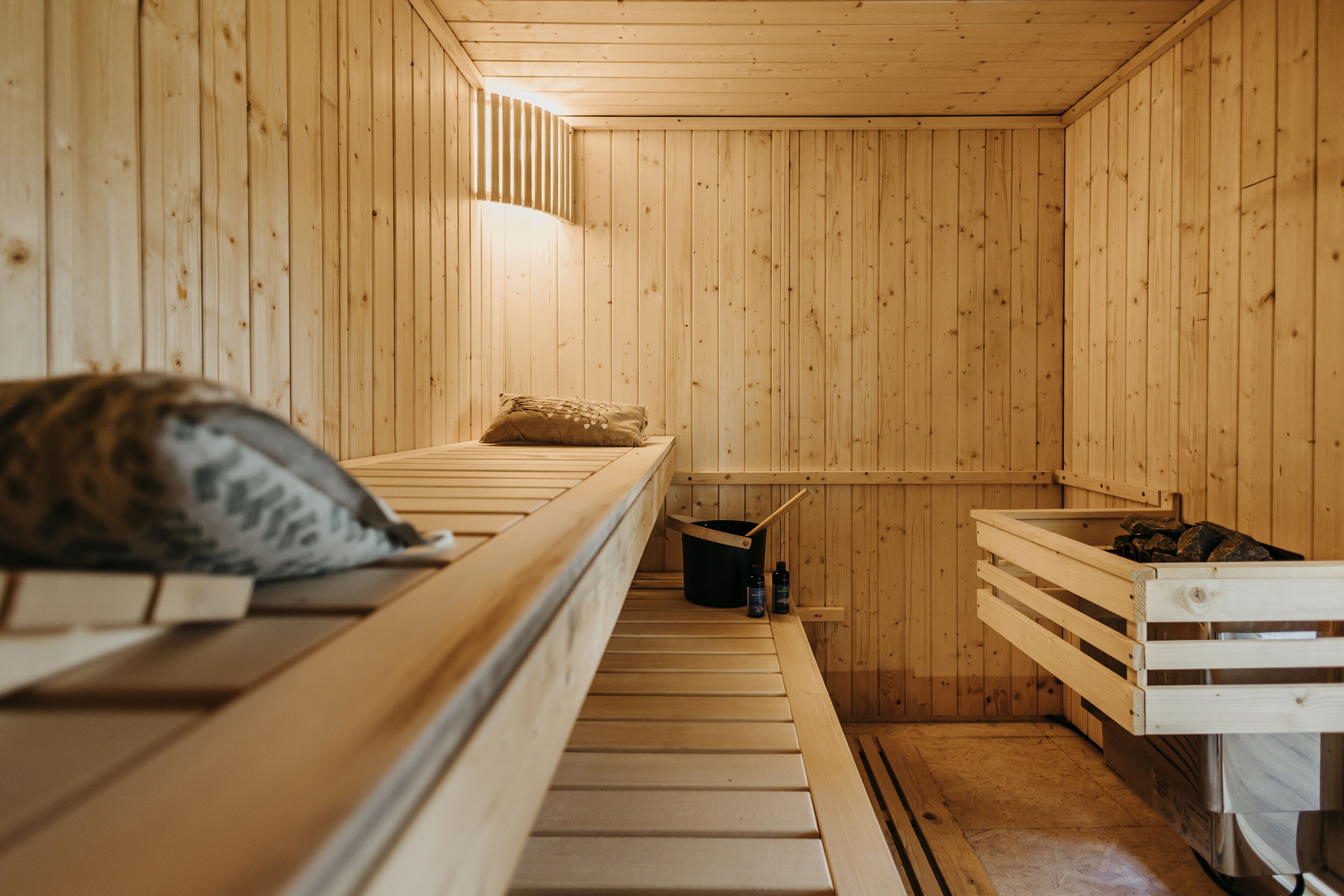 Un sauna de madera con bancos y un balde.