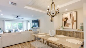 A modern dining area with a wooden table, bench, and a chandelier. - Fenced Yard, 4 Mi to Stuart Beach: Family Retreat! (Stuart)