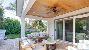 An outdoor patio with wooden furniture, a ceiling fan, and a glass door leading to a backyard. - Fenced Yard, 4 Mi to Stuart Beach: Family Retreat! (Stuart)