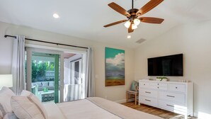 A bedroom with a bed, a ceiling fan, a TV, a dresser, and a sliding glass door leading to an outdoor area. - Fenced Yard, 4 Mi to Stuart Beach: Family Retreat! (Stuart)