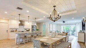 A modern kitchen with a dining area, wooden flooring, and pendant lighting. - Fenced Yard, 4 Mi to Stuart Beach: Family Retreat! (Stuart)