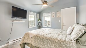 A bedroom with a bed, ceiling fan, TV, windows, and a door. - Renovated Ocean City Retreat - Walk to Beach! (Ocean City)