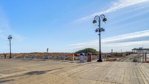 A wooden boardwalk with benches and trash bins, leading to a beach area. - Renovated Ocean City Retreat - Walk to Beach! (Ocean City)