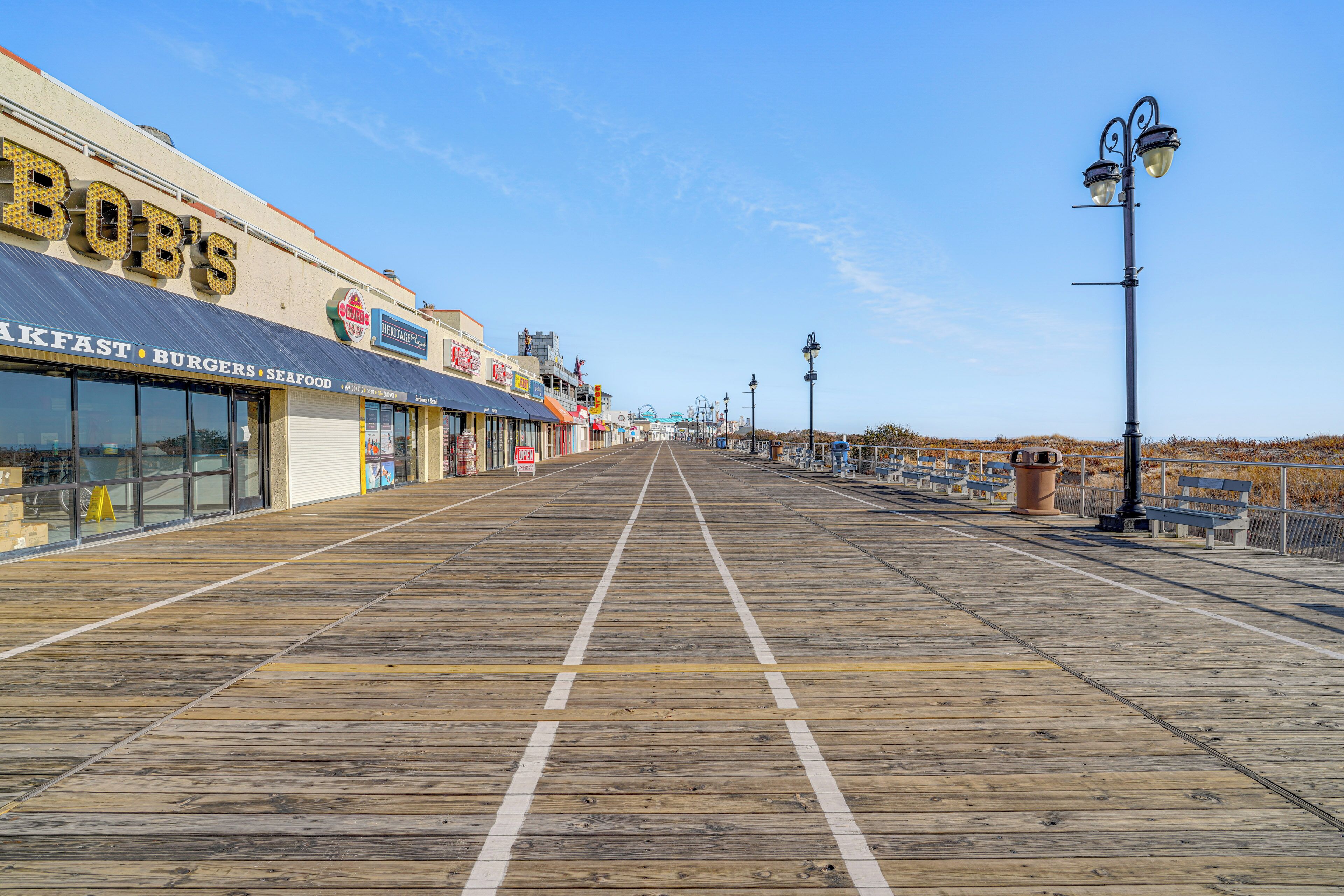Une promenade en bord de mer bordée de boutiques, dont un restaurant de fruits de mer et un restaurant de hamburgers.